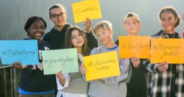 Jugendliche halten Schilder mit Demokratiebegriffen hoch